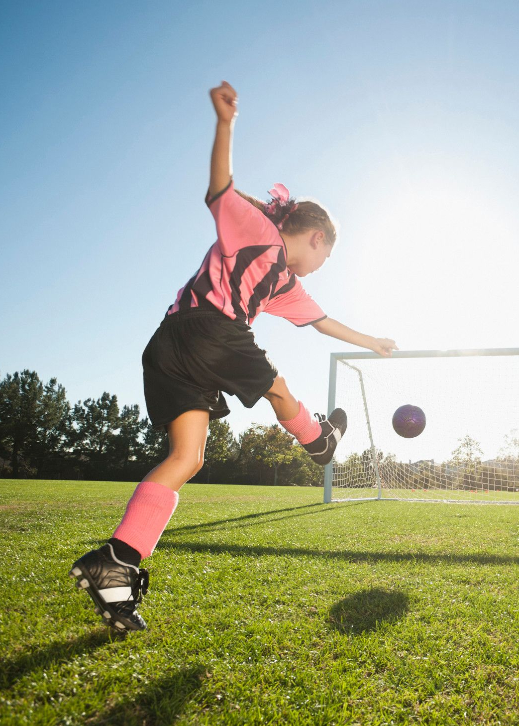 Dívka kope fotbalový míč do brány