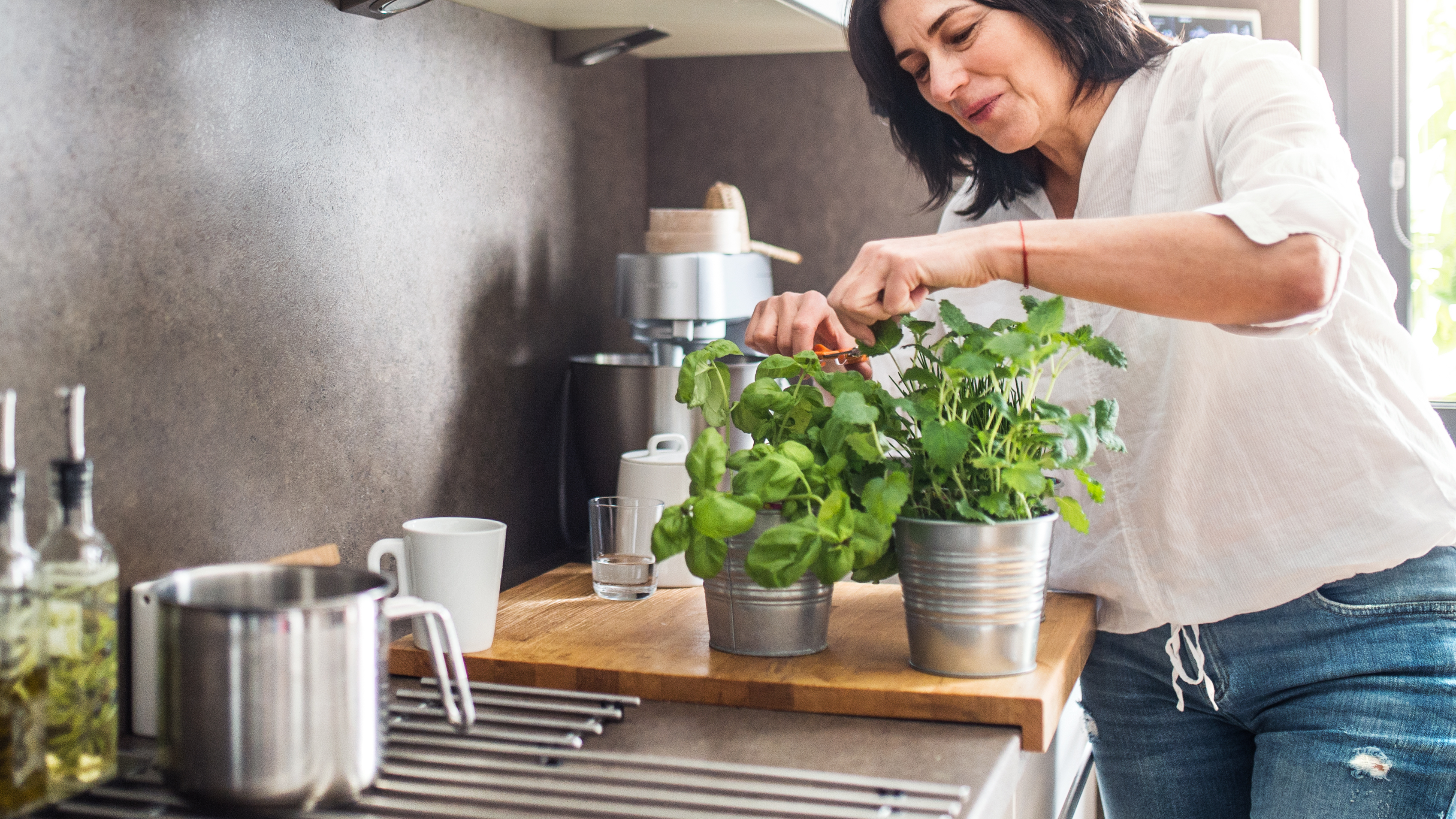 Žena stříhá v kuchyni bylinky
