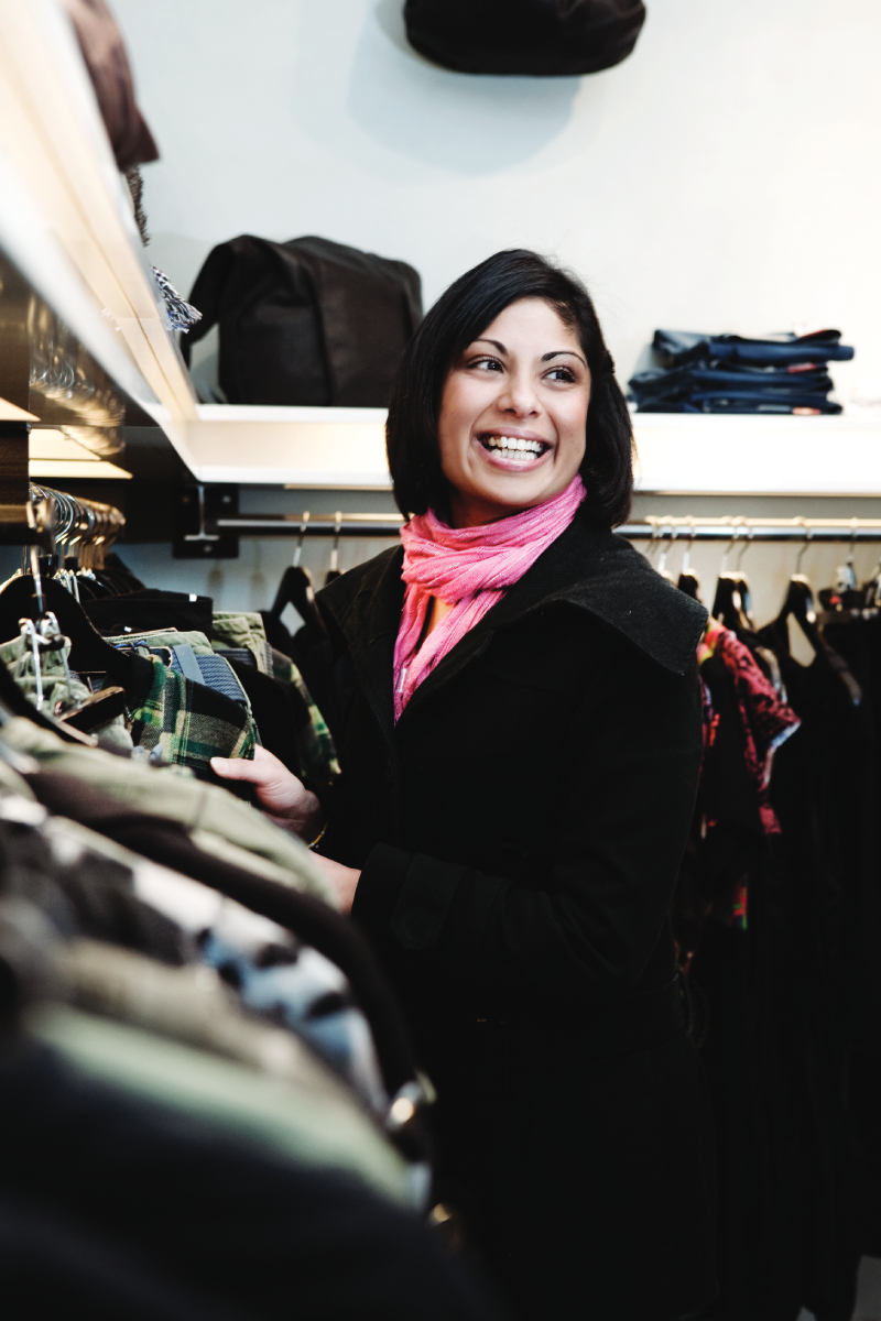 Smějící se žena vybírající oblečení v obchodě
